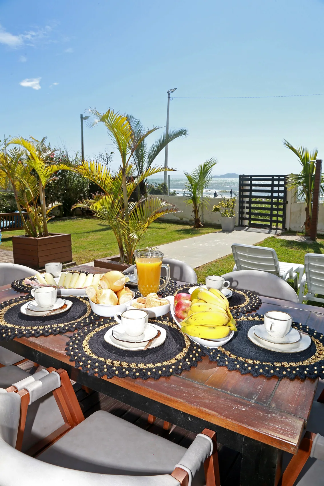 Mesa posta junto ao jardim com o mar ao fundo